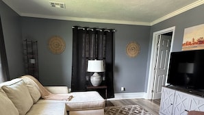 A living room with a sectional sofa, a coffee table, a TV, a fireplace, and a patterned rug.