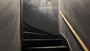 A staircase with a handrail, a light fixture at the top, and walls with a textured surface.