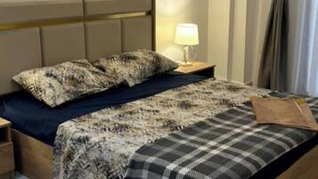 A bedroom with a bed, nightstand, lamp, and a wall decoration.