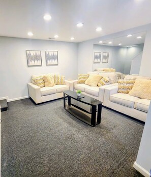A living room with a sectional sofa, a coffee table, and a large mirror. - 30+ day stay. Move-in ready! Utilities included (Fredericksburg)