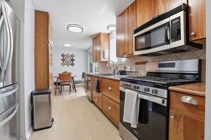 Una cocina moderna con armarios de madera, electrodomésticos de acero inoxidable y un comedor con mesa y sillas.