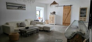 A living room with a sofa, ottoman, coffee table, and a glass cabinet. - "OasisLajares" charming house with swimming pool and exotic garden in Lajares. (Lajares)