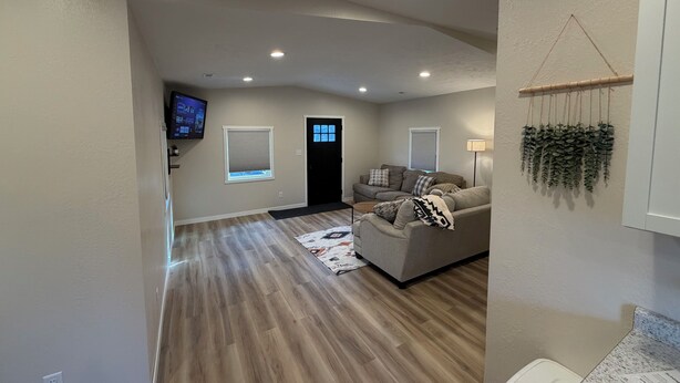 A living room with a sofa, a television, and a wall-mounted plant.