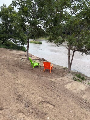 Een zandstrand met twee stoelen en een boom.