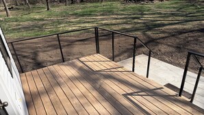A wooden deck with metal railings, leading to a grassy area.