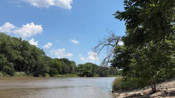 Une rivière dont les berges sont sablonneuses et qui est bordée d’une végétation luxuriante d’un côté.