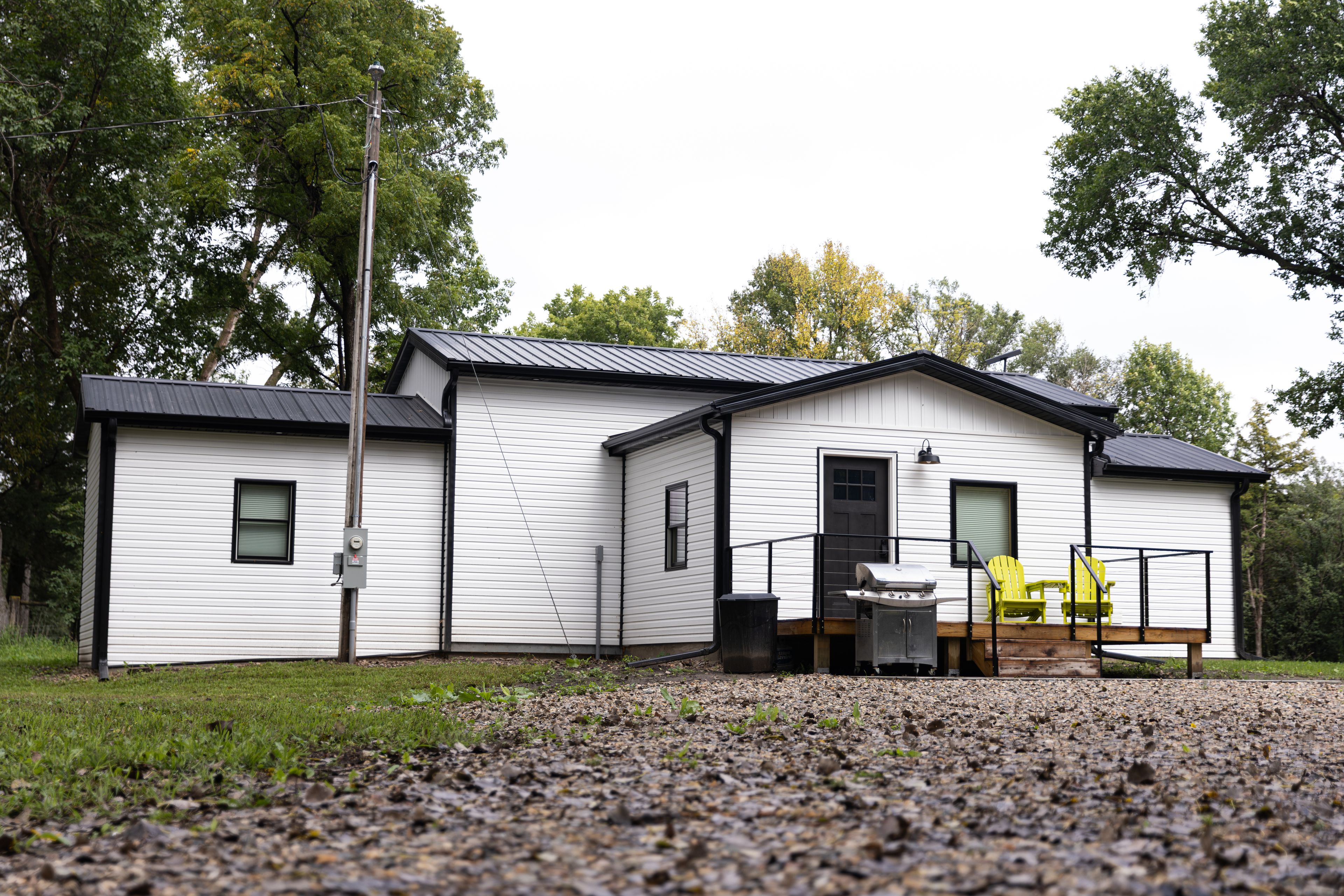 A single-story building with a metal roof, a front porch with a grill, and a small deck area.