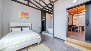 A bedroom with a bed, a painting, a bathroom with a bathtub, and a dining area with a table and chairs.
