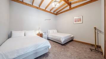 A bedroom with two beds, a ceiling fan, a radiator, and a framed picture on the wall.