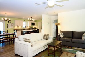 A living room with a white sofa, a dark sofa, a wooden coffee table, and a ceiling fan. - Rehoboth Beach House Pet Friendly Fenced Yard Next to Trail (Rehoboth Beach)