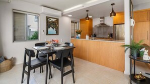 A modern kitchen with a dining area, featuring a central island, pendant lighting, and a view of the outside. - Roberts Street Retreat - Taupo CBD (Taupo)