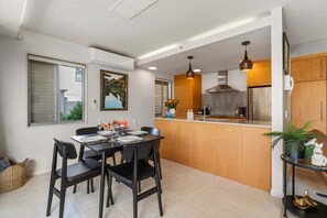 A modern kitchen with a dining area, featuring a central island, pendant lighting, and a view of the outside. - Roberts Street Retreat - Taupo CBD (Taupo)