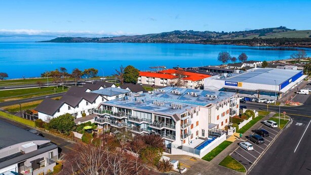 A modern hotel with a rooftop terrace, a parking lot, and a view of a lake. - Roberts Street Retreat - Taupo CBD (Taupo)