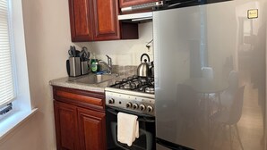 A kitchen with wooden cabinets, a stainless steel stove, a microwave, and a refrigerator.