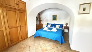 A bedroom with a bed, wooden wardrobe, and an arched doorway. - Domus Floris Positano (Positano)