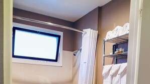 Een badkamer met een bad, toilet en een raam.
