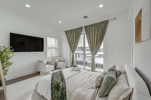 Ein modernes Hotelzimmer mit einem großen Bett, einem Flachbildfernseher, einer Couch und einem Balkon mit Blick auf die Stadt.