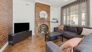 Een woonkamer met een haard van baksteen, een flatscreentelevisie, een bank en een salontafel.