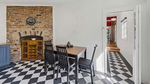 Een eetruimte met een geruite vloer, een bakstenen muur en een houten kast.