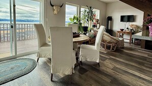 Un vaste espace de vie doté d’une grande fenêtre offrant une vue panoramique, d’une table à manger avec des chaises et d’une décoration murale représentant une tête de taureau.