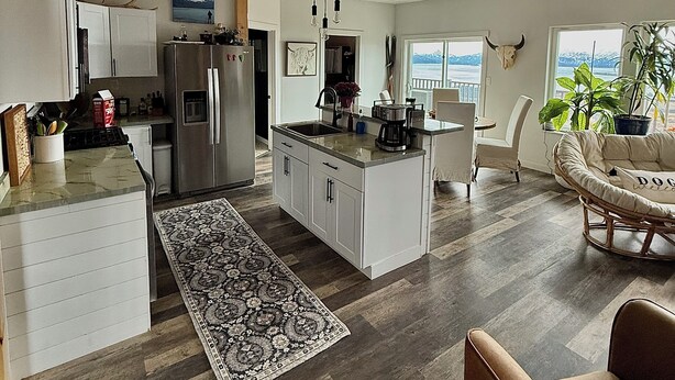 Une cuisine spacieuse dotée d’un îlot central, de parquets en bois et offrant une vue sur l’extérieur.
