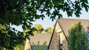 Un bâtiment en pierre doté d’un toit triangulaire, entouré de verdure.