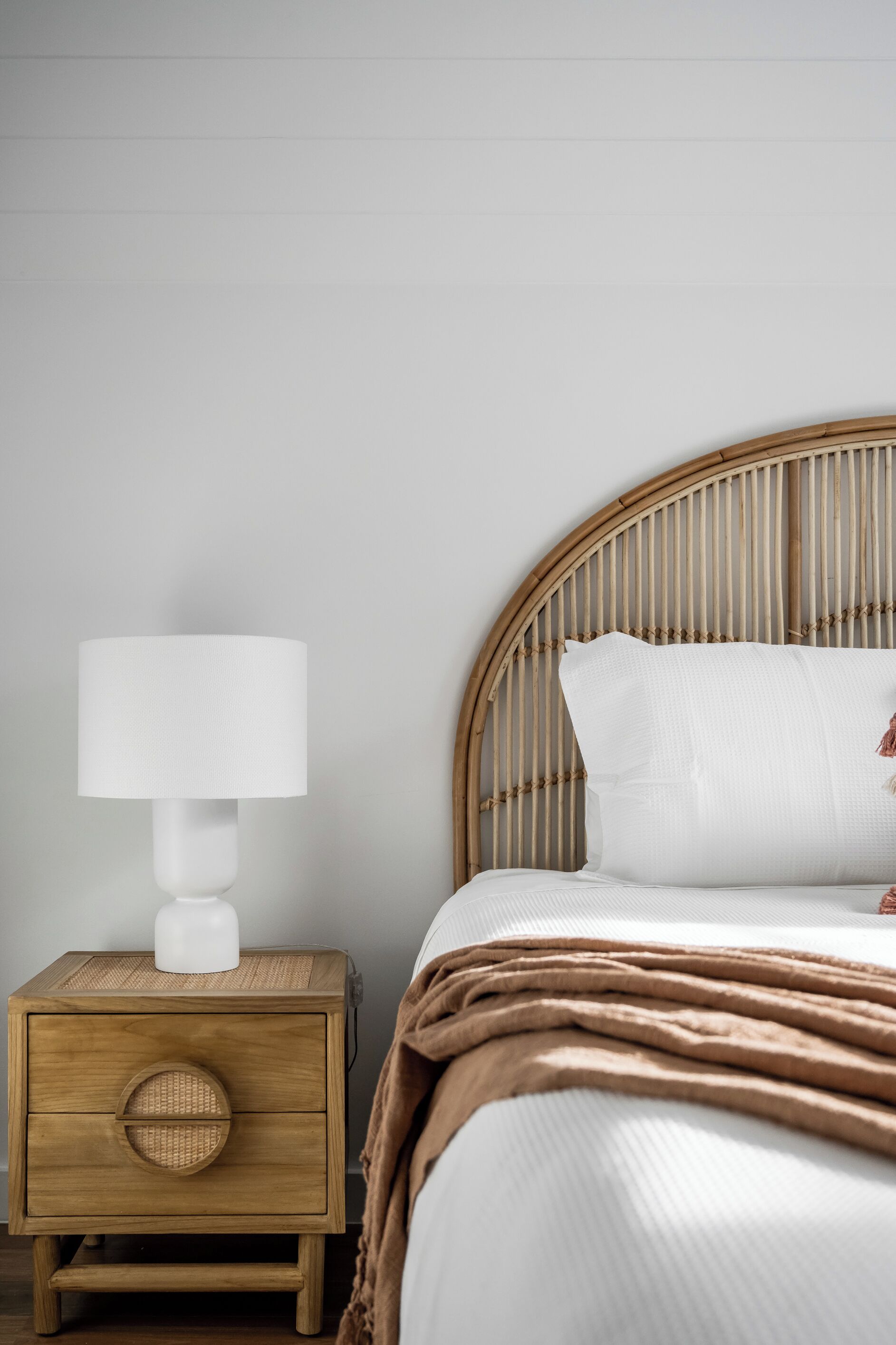 A bed with a headboard, a bedside table with a lamp, and a drawer.