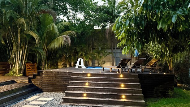 A pool area with steps leading to lounge chairs, surrounded by greenery. - 3-bedroom house in lovely Fort Lauderdale with AC (Fort Lauderdale)