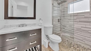 A modern bathroom with a marble vanity, a toilet, and a glass shower enclosure. - 3-bedroom house in lovely Fort Lauderdale with AC (Fort Lauderdale)