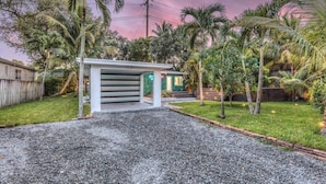 A residential property with a covered driveway, palm trees, and a house with a green roof. - 3-bedroom house in lovely Fort Lauderdale with AC (Fort Lauderdale)