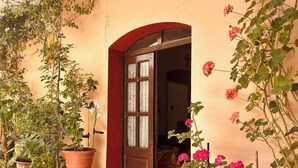 Un acceso cubierto con puerta de madera, plantas en macetas y suelo de baldosas.