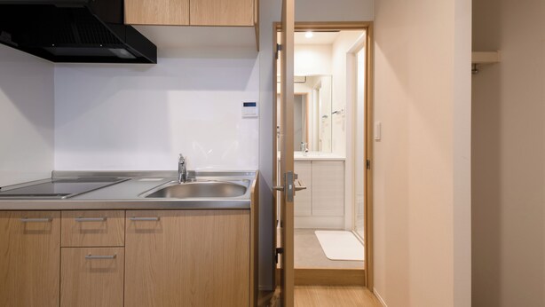 A modern kitchen with wooden cabinets, a black range hood, and a stainless steel sink. - TD STAY TOKYO (Tokyo)
