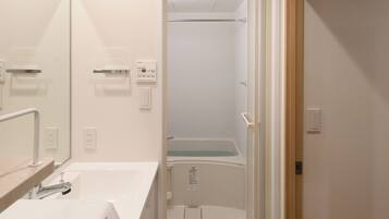 Une salle de bain moderne équipée d’un lave-linge intégré, d’un miroir et d’un espace douche.