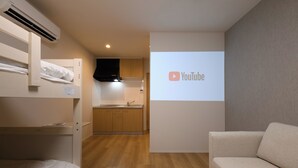 A room with bunk beds, a kitchenette, and a projection screen displaying the YouTube logo. - TD STAY TOKYO (Tokyo)