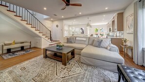 Un vaste espace de vie comprenant un escalier, un ventilateur de plafond, un canapé, une table basse et un coin repas.