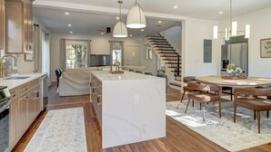 Une cuisine moderne dotée d’un îlot central, de meubles en bois et de luminaires suspendus.