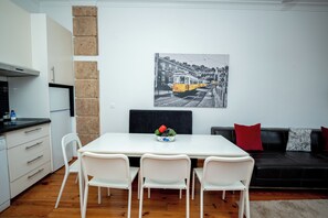 Eine moderne Küche mit weißen Schränken, einer schwarzen Arbeitsplatte und einem Essbereich mit weißem Tisch und Stühlen.