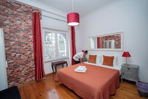 Ein Schlafzimmer mit einem Bett, einem Fenster, einem Spiegel und einer roten Lampe.