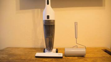 Una aspiradora blanca y una herramienta eléctrica sobre una mesa de madera.