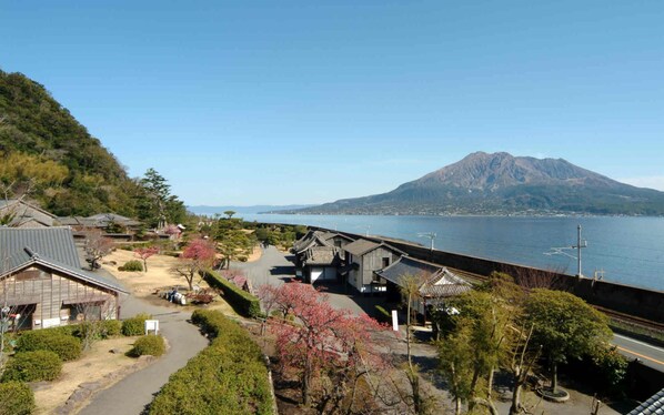 A coastal area with traditional buildings, a bridge, and a mountain in the background.