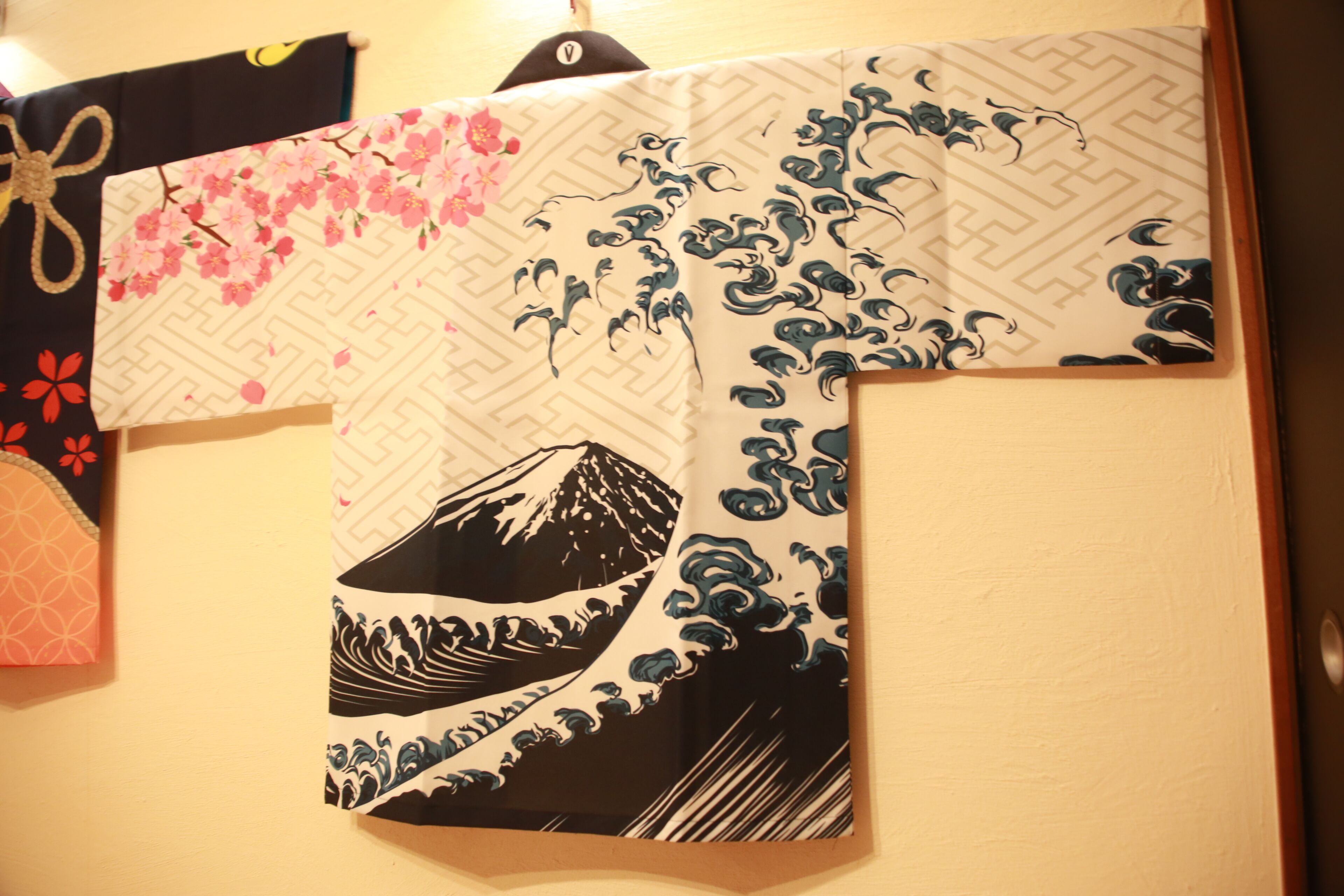 Een kamer met een traditioneel Japans shoji-scherm, een houten deur en een wandgemonteerd shoji-scherm met bloemenmotieven.