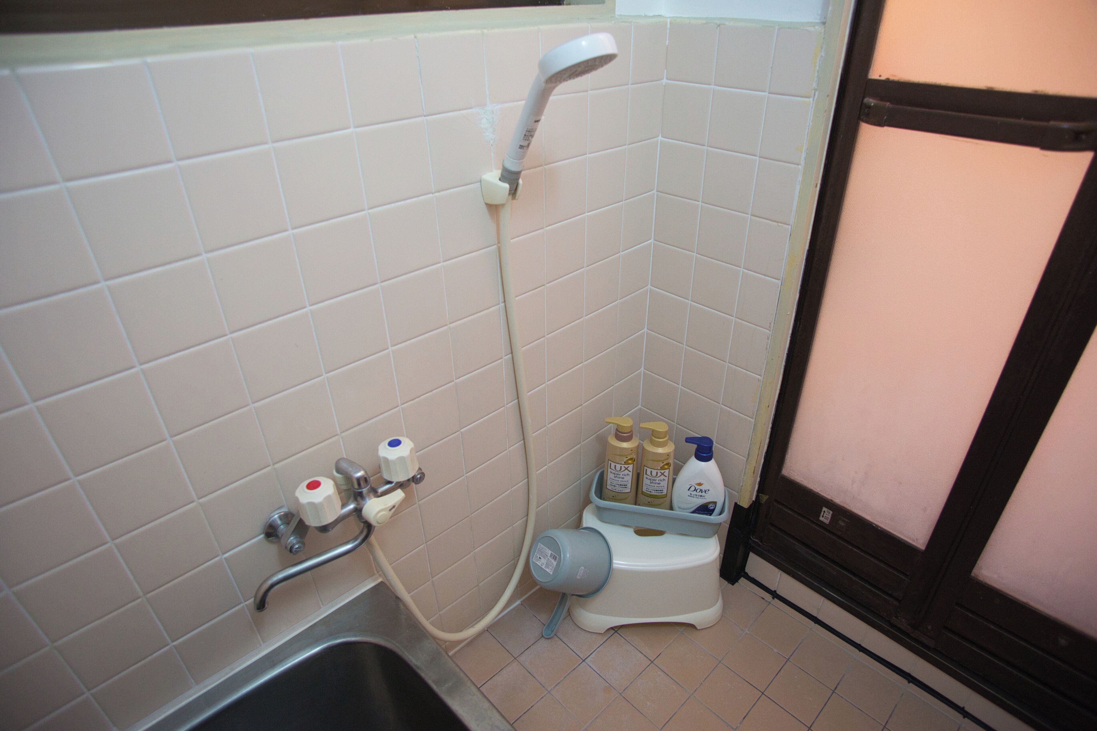 Un baño pequeño con ducha, inodoro y lavamanos. Hay artículos de aseo en el inodoro.