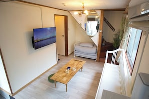 A room with a bed, a table with glasses, a TV, and a staircase.