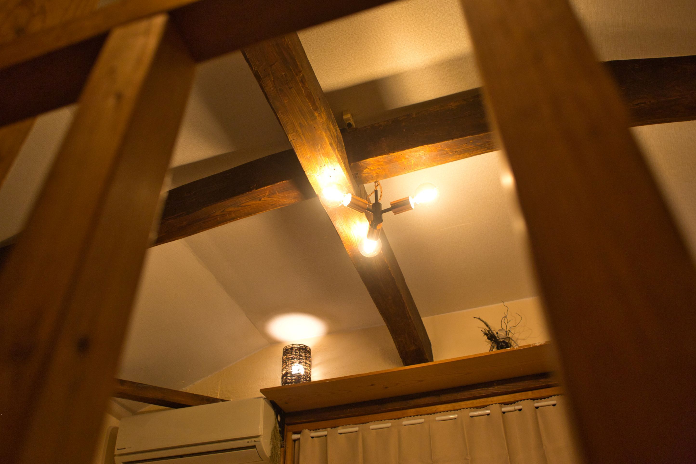 A ceiling with exposed wooden beams and recessed lighting.