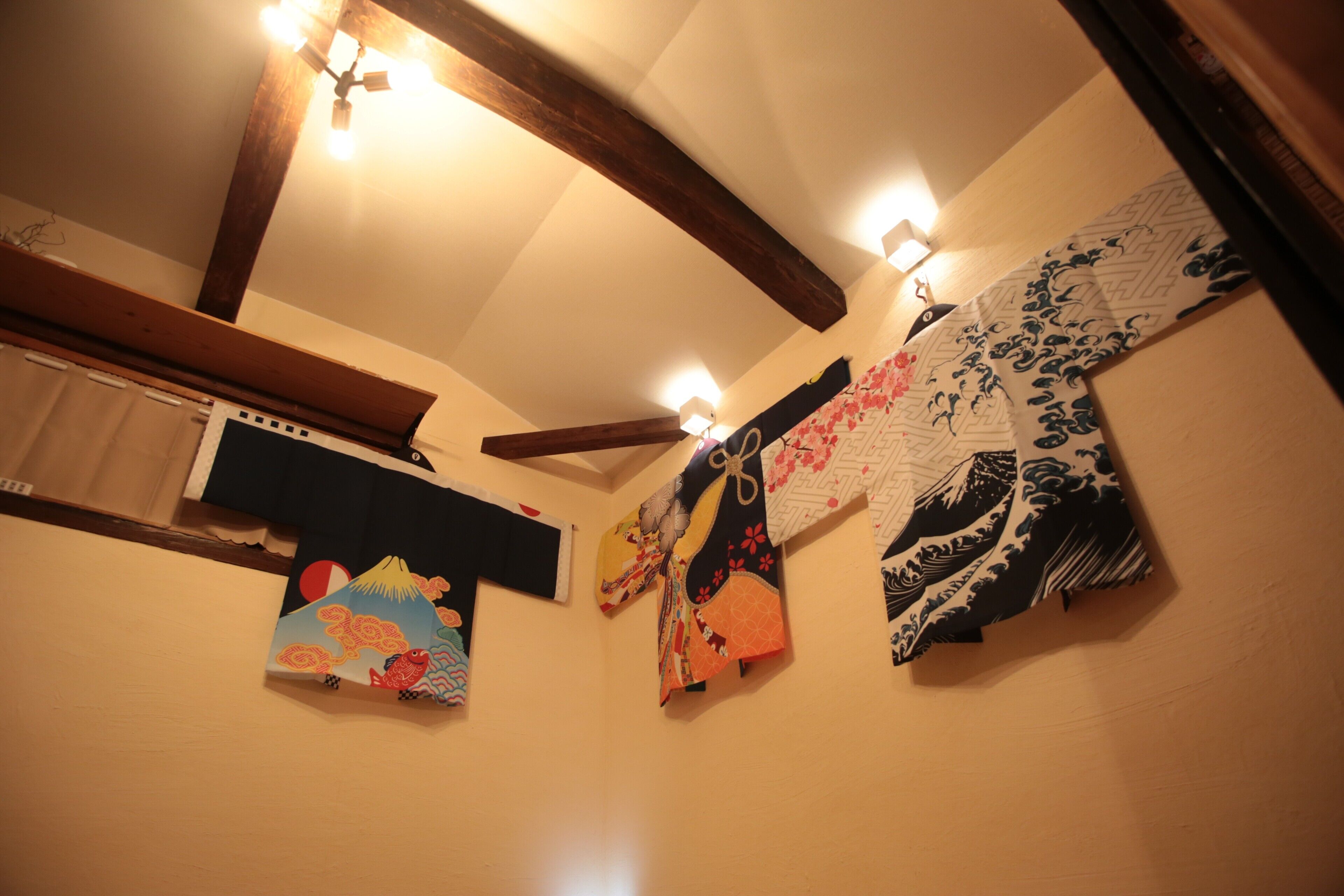 A room with wooden beams, a ceiling fan, and wall-mounted lights.