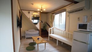 Un espacio habitable compacto con una mesa de madera, un banco, un microondas y un refrigerador.