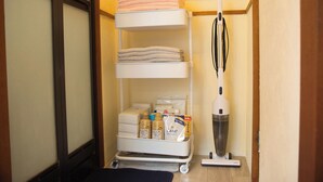 Un carrito de almacenamiento con toallas, artículos de aseo y una aspiradora en una habitación de hotel.