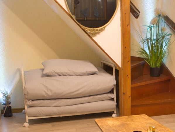 A bunk bed with a pillow, a wooden table, and a potted plant.