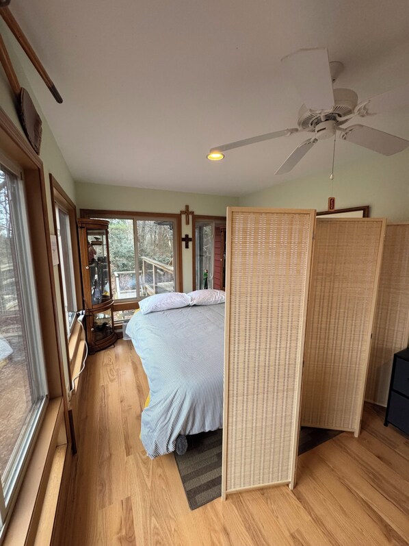 Un dormitorio con una cama, ventilador de techo, ventana y vistas al exterior.