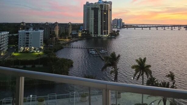 A high-rise building with a waterfront view, a bridge, and a pool area with sun loungers. - Lux in Black 2BR Bay, Pool & Ocean Views (Fort Myers)